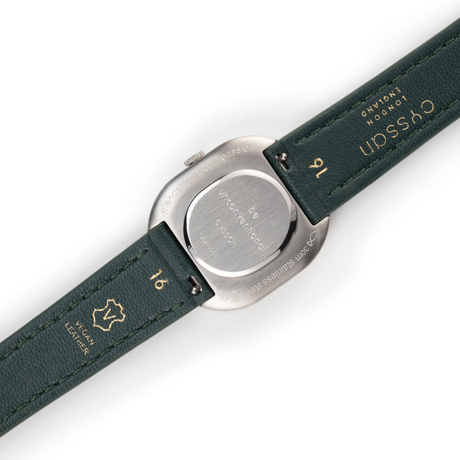 cae back view showing engraved silver watch case and forest-green vegan-leather strap.
