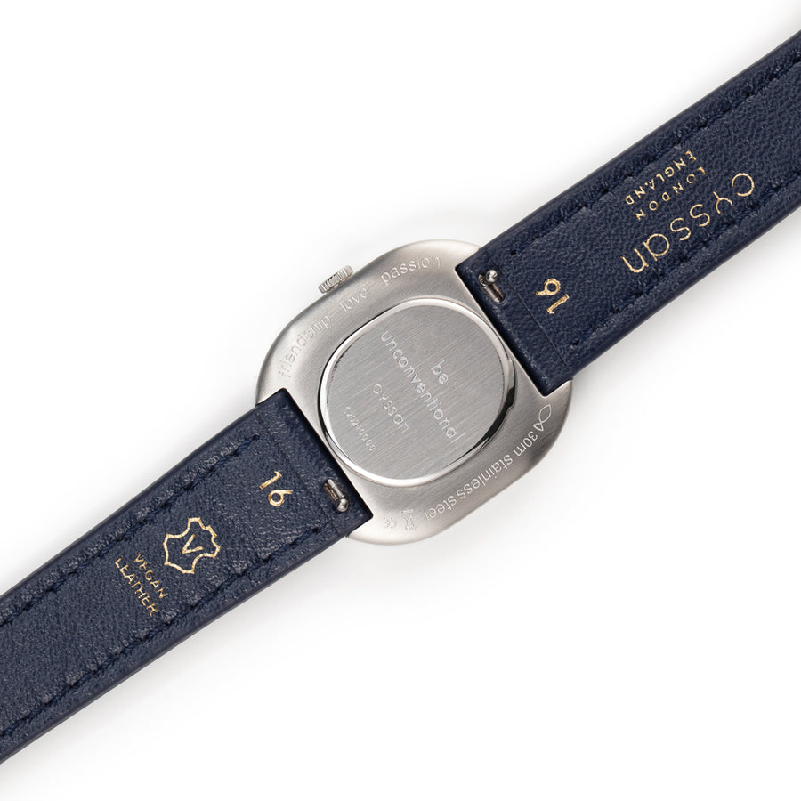 View of the engraved silver case back and dark blue vegan-leather strap.