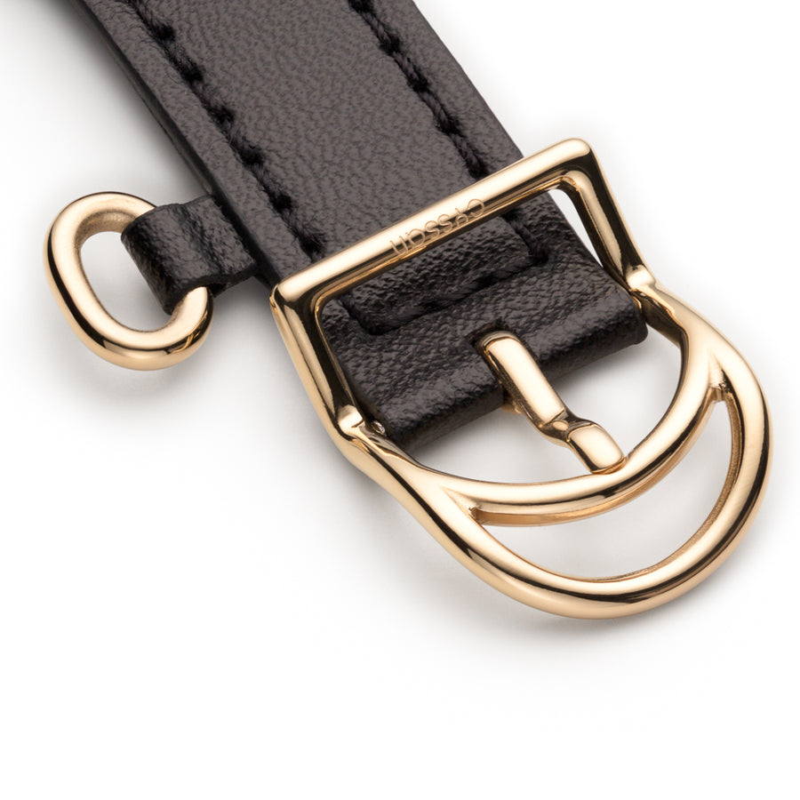 close up of gold buckle, and gold ring detail on black vegan-leather watch.