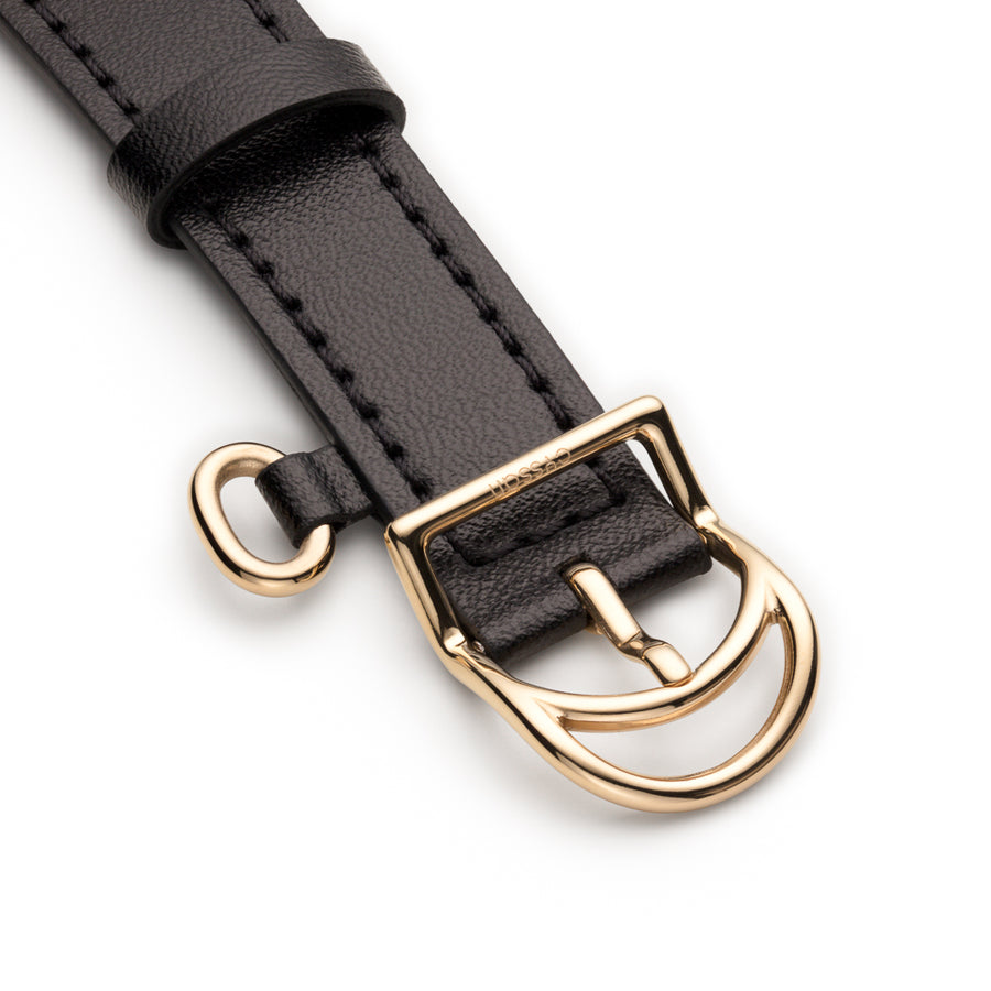 black watch strap with yellow-gold buckle engraved with the word Cyssanand ring embellishment on side of strap