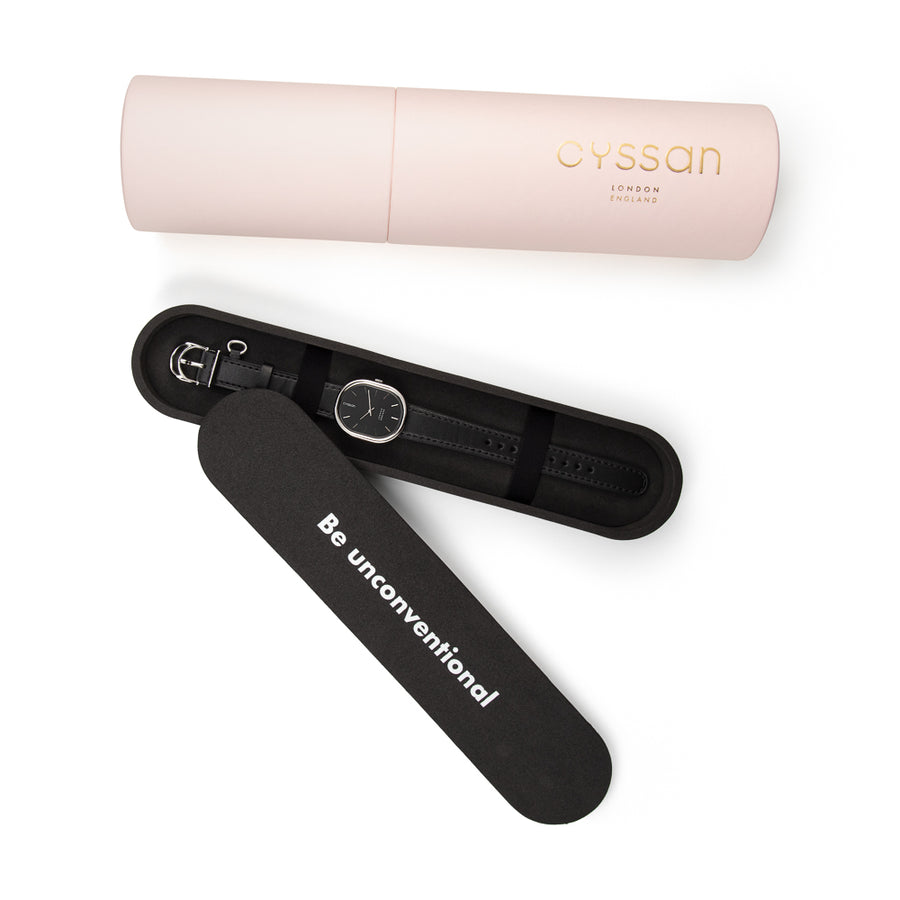 the Cyssan pink cylindric packaging. The black-EVA foam inner packaging is open and there is a watch with a stainless steel watch case and black watch strap placed inside. It is held in place with two black elastic straps.