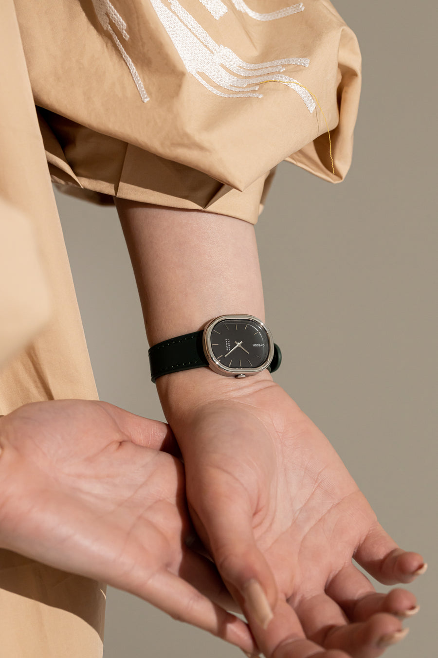 model wearing cyssan watch with black dial, silver case, silver index and hands, and black vegan-leather strap