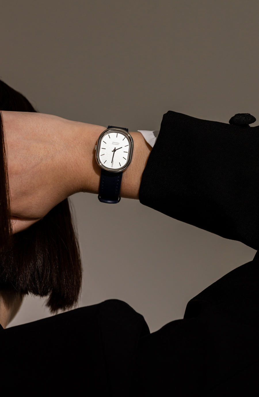 a model wearing a cyssan watch with a silver case, silver dial, index and hands, and a black vegan-leather strap